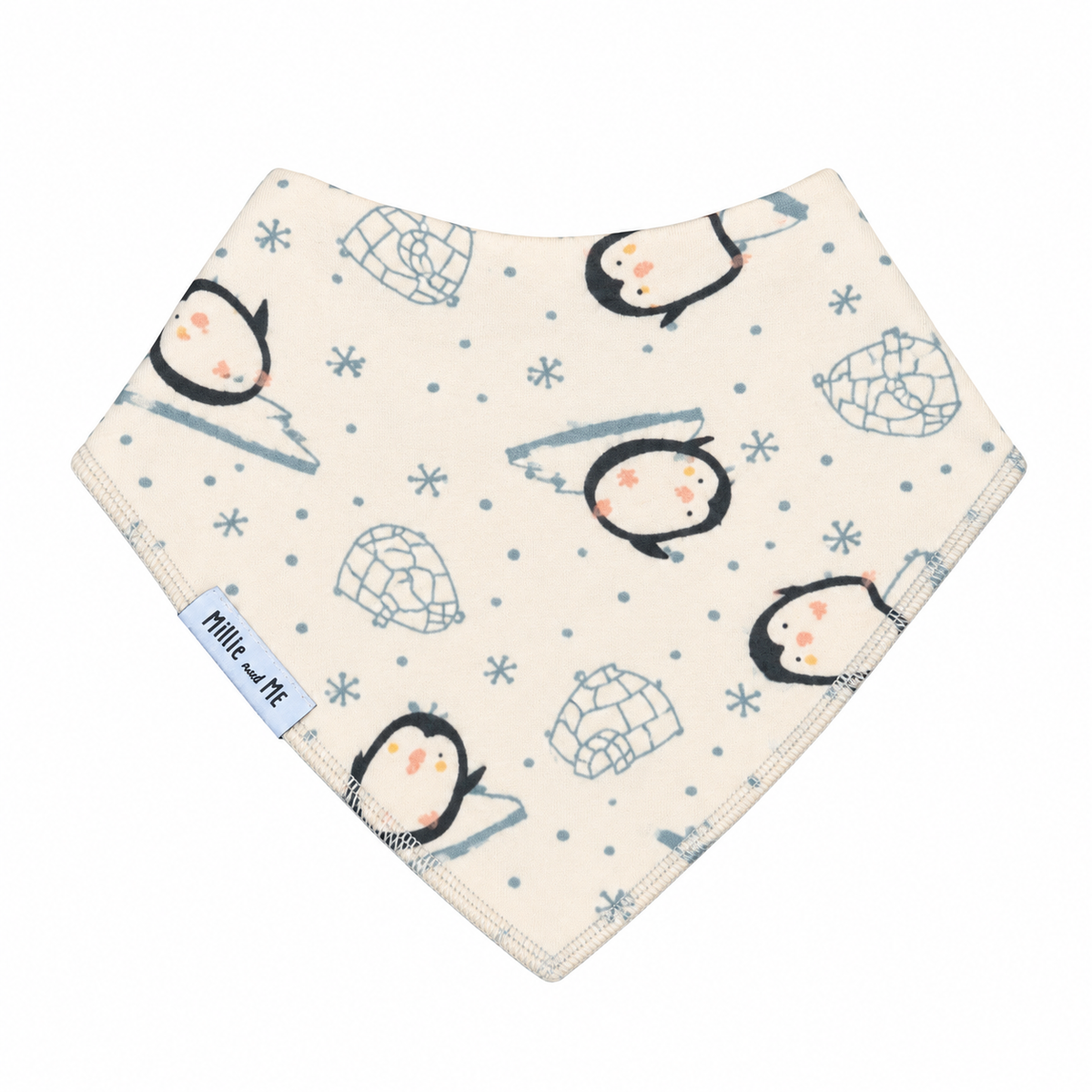 A triangular baby bib with a penguin and icy pattern on a cream background, featuring a light blue fabric brand tag that reads 'Millie and Me'.