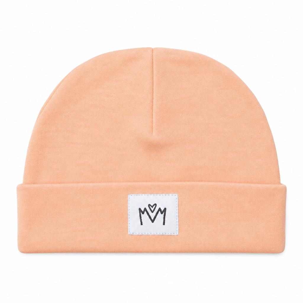 Peach-coloured baby beanie hat with a folded cuff and Millie and Me logo, photographed on a white background.