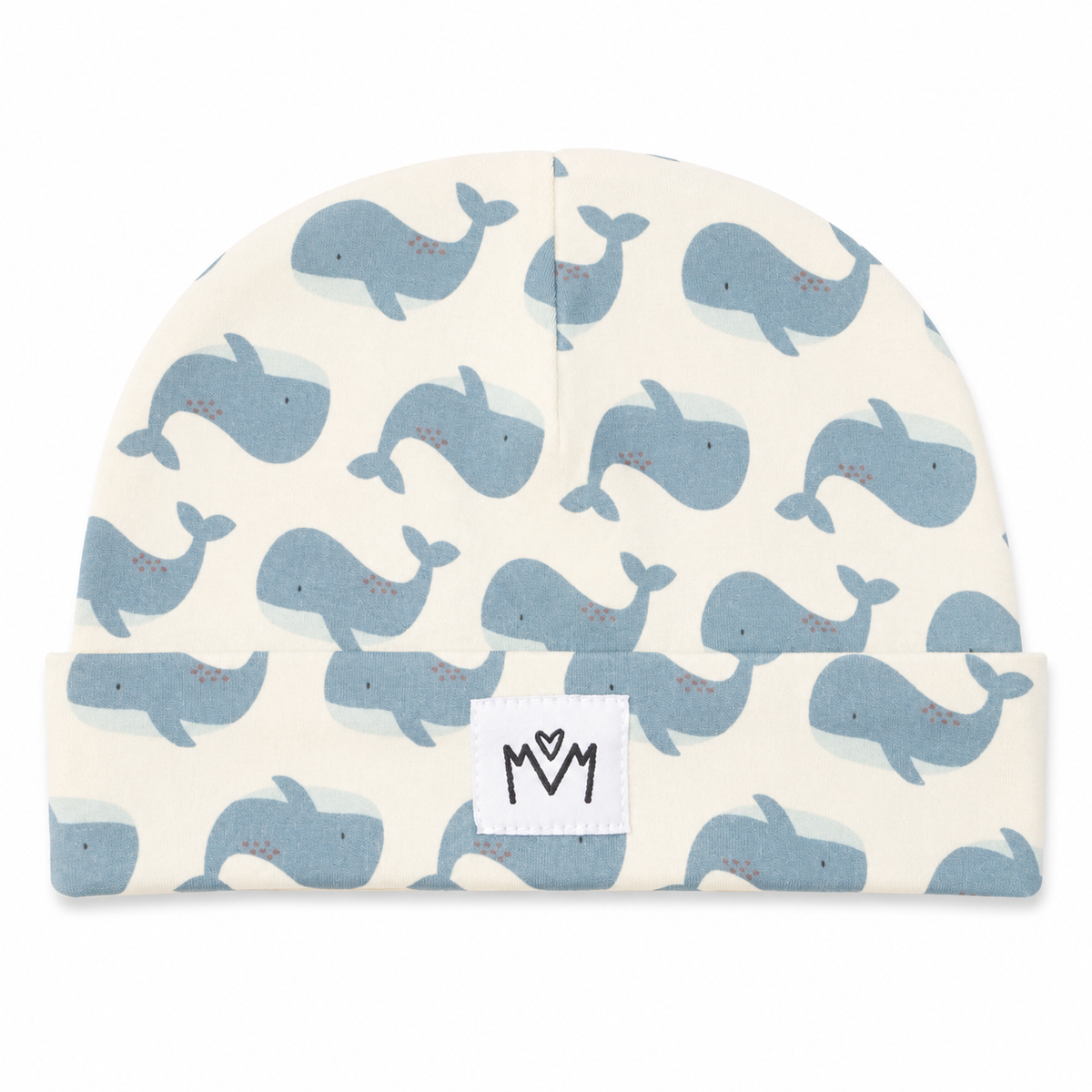 A baby beanie hat featuring a repeating pattern of light blue whales on an off-white background, with a white fabric patch on the cuff displaying a black hand-drawn 'MM' logo.