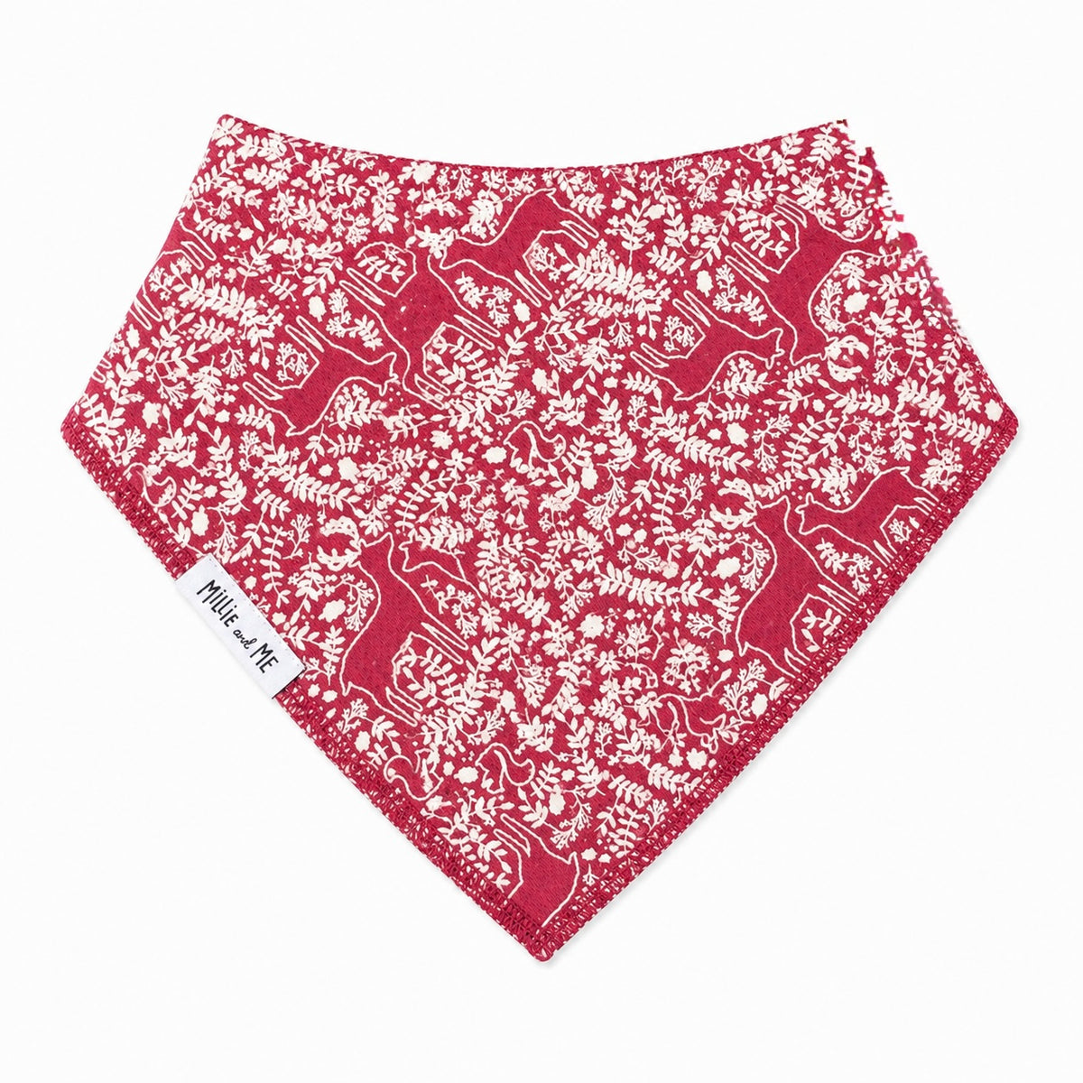 A triangular bandana-style pet bib in red with a white floral and deer pattern, featuring a small white fabric tag with the text 'Millie and Me'.
